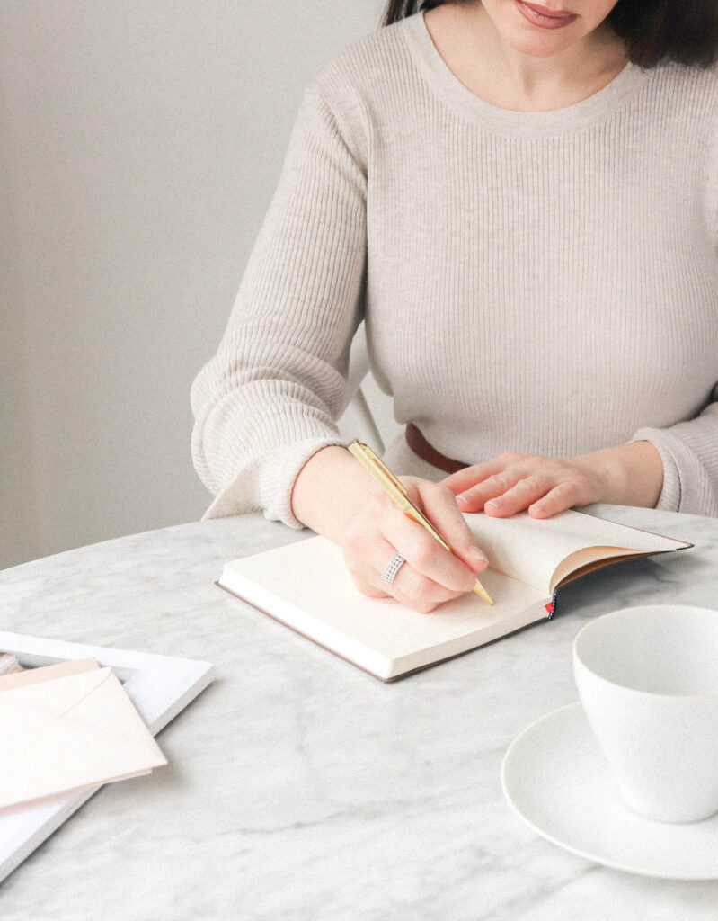 Woman sitting at table writing in a notebook.